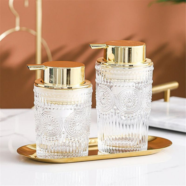 Dispenser sapone in vetro dosatore dorato.